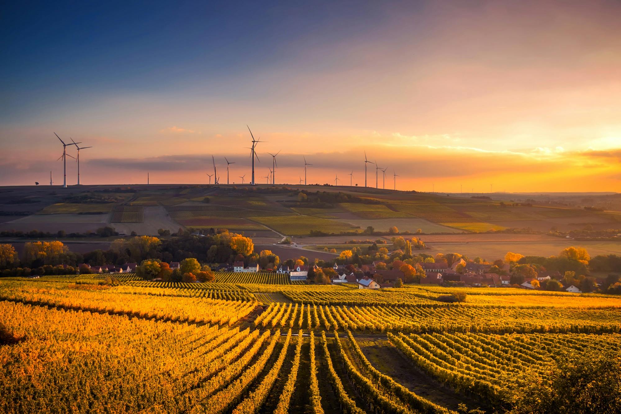 Breathtaking view of a countryside landscape with wind turbines and vivid sunset.