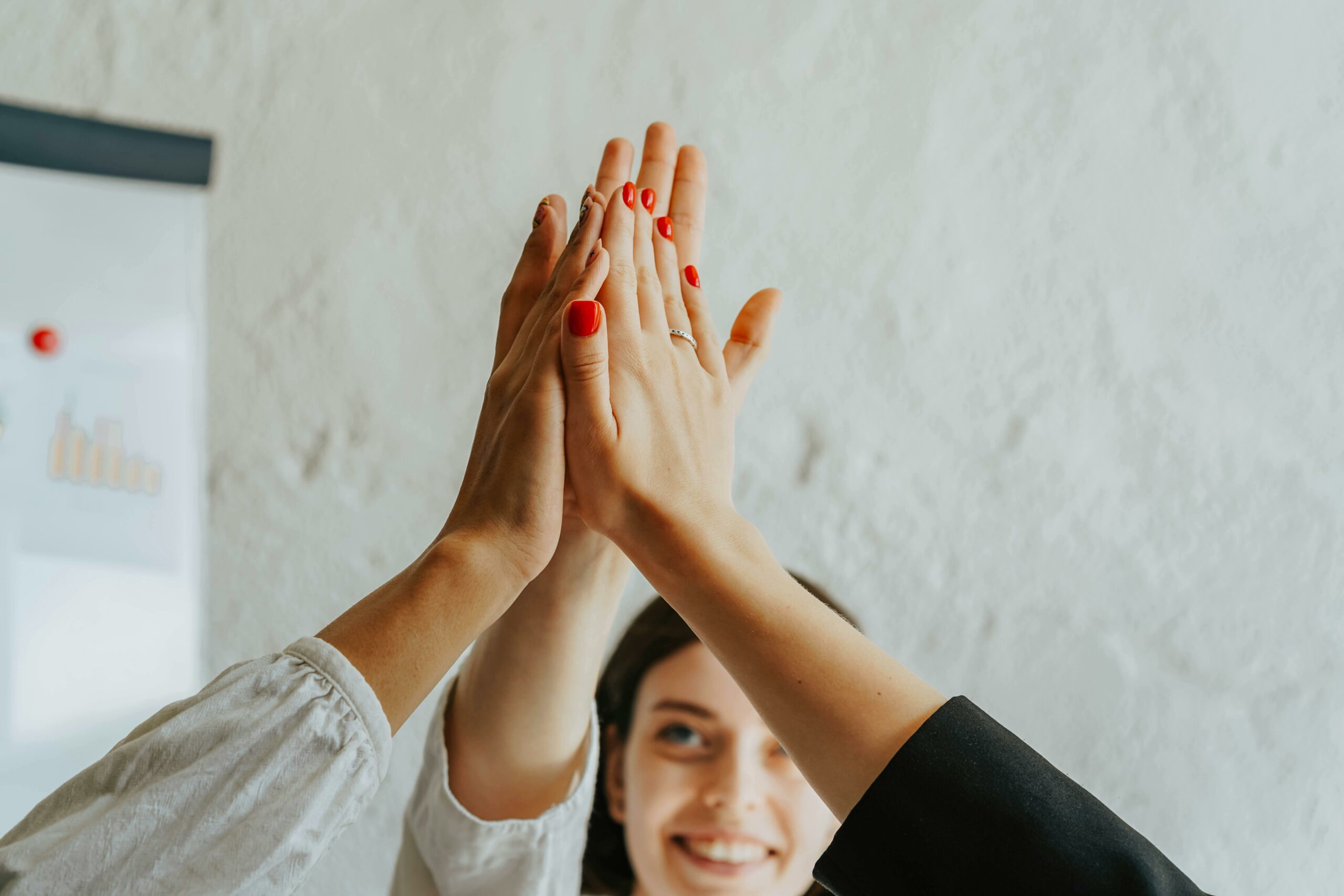 A close-up of a group high five, representing teamwork and achievement in a professional setting.