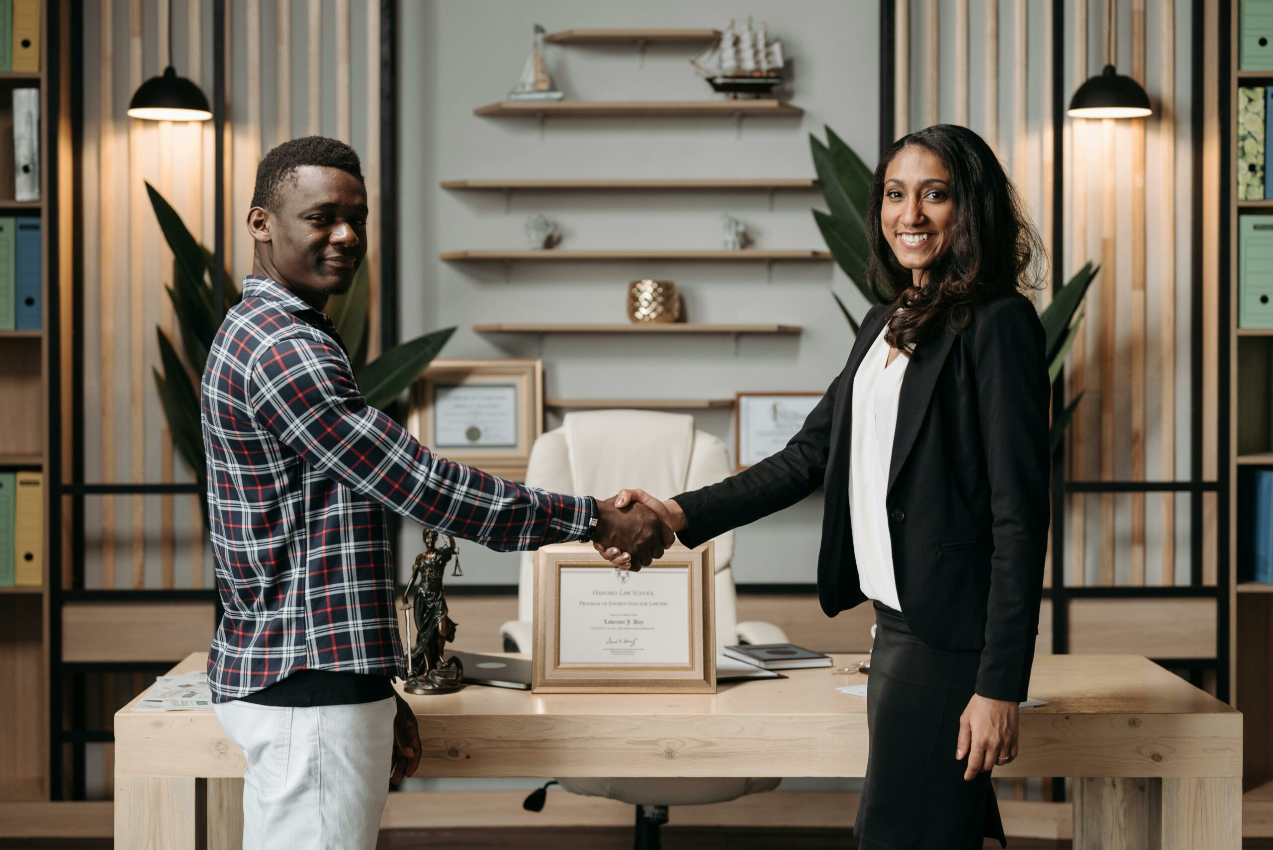 Two professionals shaking hands in an office setting, symbolizing business agreement.